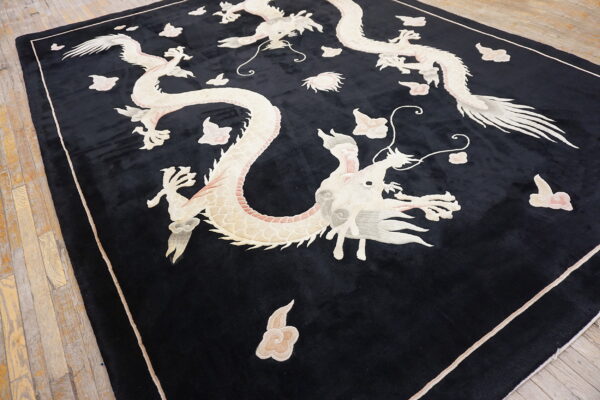 Plush black rug displaying intricate ivory and pale pink dragon and cloud patterns on wood flooring.