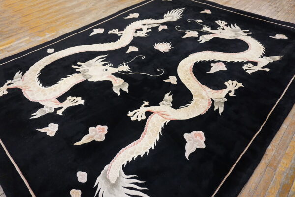 Plush black rug with pale dragon and cloud designs, resting on wide plank wood flooring.
