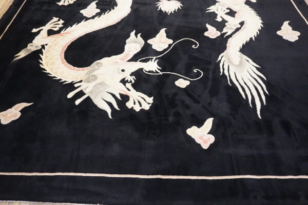 Detailed view of a black rug with large light-colored dragon and cloud motifs.