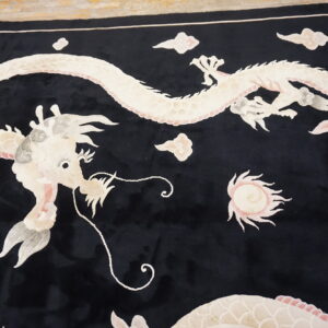A velvety black rug displays a detailed white and pink dragon pattern with surrounding stylized clouds.
