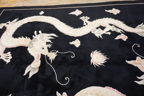 A velvety black rug displays a detailed white and pink dragon pattern with surrounding stylized clouds.