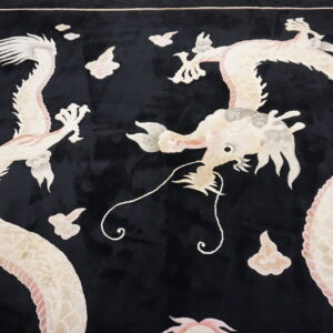 A black plush rug features an elaborate design of two cream and pink dragons amidst sculpted clouds.