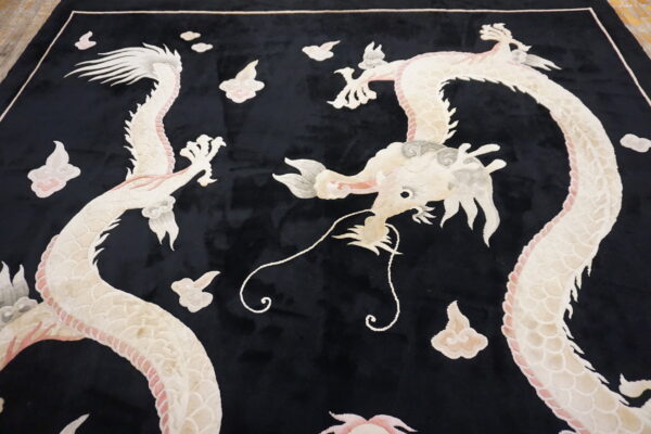 A black plush rug features an elaborate design of two cream and pink dragons amidst sculpted clouds.