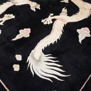 Black cut-pile rug featuring a large, detailed ivory and pink dragon and cloud pattern on wood flooring.