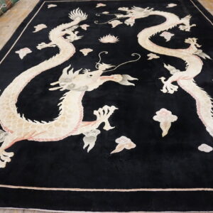Black high-pile rug with sculpted ivory and pink twin dragon pattern on light wood flooring.