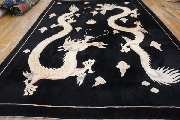 Black high-pile rug with sculpted ivory and pink twin dragon pattern on light wood flooring.