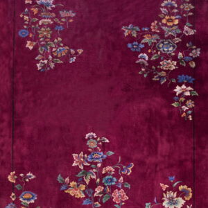 A vibrant, deep red rug featuring scattered blue, yellow, and pink floral patterns framing the central field.