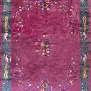 Magenta rug with a blue-green border patterned with colorful birds and a central floral medallion.