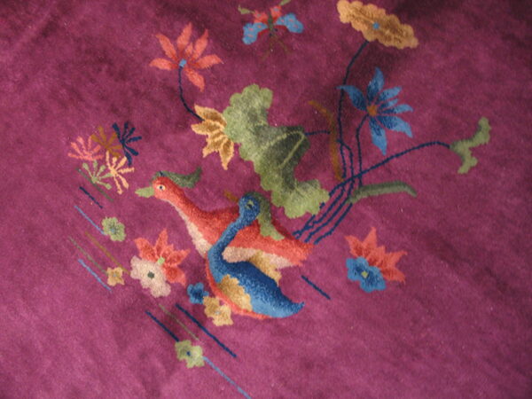 Textured purple rug detail showing colorful geese, blue and orange flowers, and green leaves.