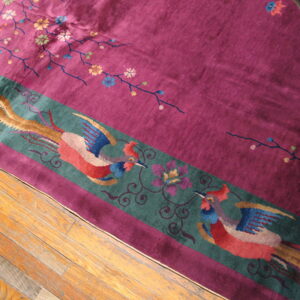 A deep purple rug with a decorative teal border featuring two stylized, colorful birds rests on wood flooring.