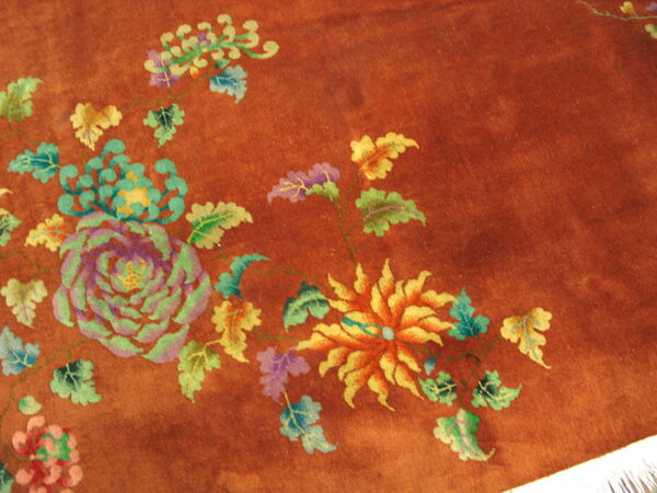 High-pile reddish-brown rug with colorful floral motifs and white fringe visible at the corner.