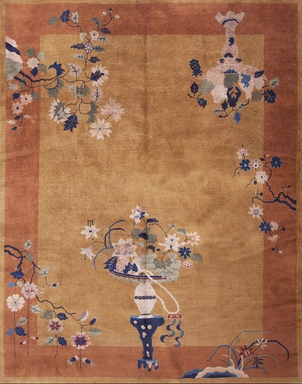 Gold and rust bordered rug with large navy and pink floral arrangements and decorative vase motifs.