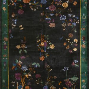 Black rug with vibrant multicolored botanicals and a striking green border framed by a thin yellow line.