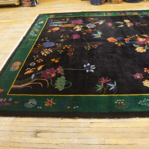 High-pile black rug with bright multicolored floral motifs and a green border, resting on distressed wood floors.