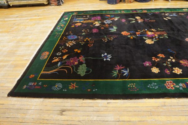 High-pile black rug with bright multicolored floral motifs and a green border, resting on distressed wood floors.