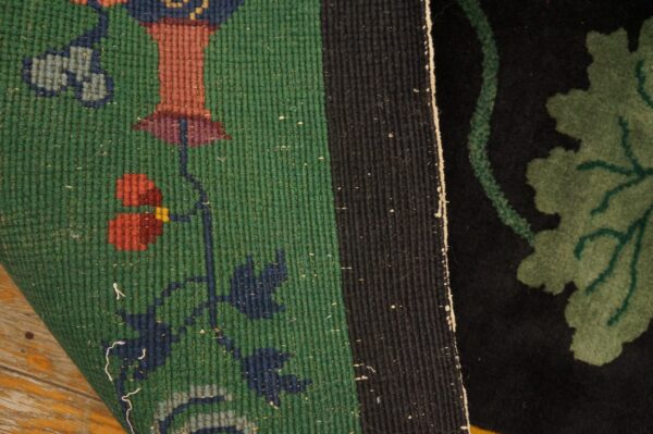 Close-up showing a green flatweave border with floral designs meeting a black cut pile field.