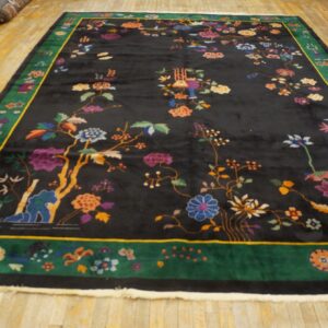 Plush black rug with vivid floral and scenic designs framed by a wide green border on hardwood floors.