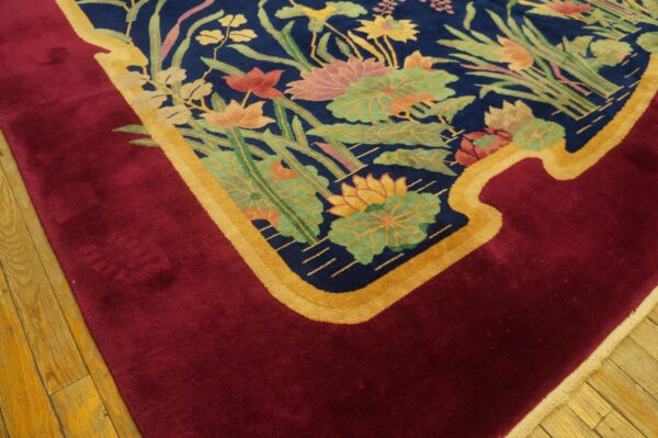 Plush rug with a navy floral field bordered by a curved gold line and solid crimson on wood flooring.