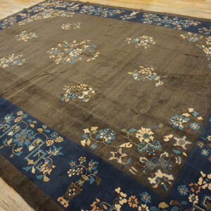 A brown rug with a deep indigo border displays scattered light blue and cream floral patterns.