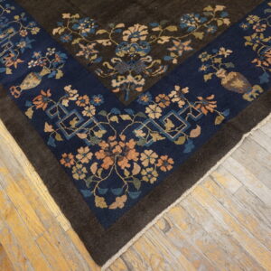 A dark brown rug corner with navy floral border rests on distressed yellow and gray wood planks.