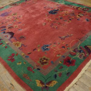 Rose and multicolored floral rug featuring wide green and brown borders on distressed wood planks.