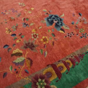 High-pile rug featuring a pink field with colorful floral vines and a contrasting green geometric border.