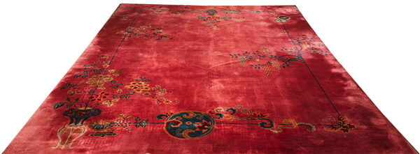 Large crimson rug with an open field and elaborate corner designs of flowers, vines, and decorative vessels.