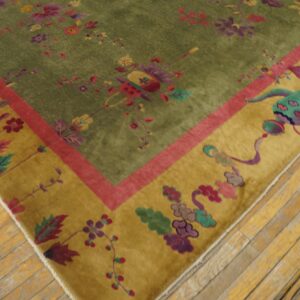 Green floral rug with a gold border and magenta stripe resting on distressed yellow hardwood.