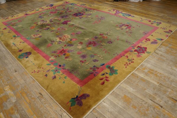 Plush green rug with abundant pink and purple florals, bordered by magenta and gold, resting on rustic wood floors.