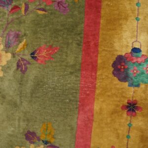 Green and gold high-pile rug with colorful floral and lantern patterns rests on wood floorboards.