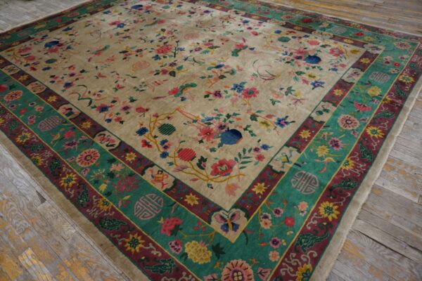 Multicolor floral rug with an ivory field and wide teal-green border lies on aged wooden planks.