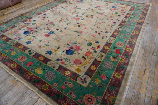 Beige rug with multicolored floral design and wide teal borders rests on rustic light gray wooden flooring.