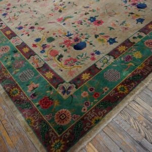 Beige rug with vibrant floral and bird motifs, framed by multi-band borders in teal and wine red, on weathered wood.