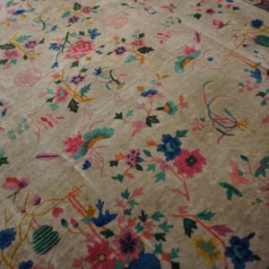 Plush beige rug with a dense multi-color floral and vine pattern extending into the border.