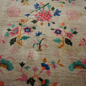 Close up of a plush cream rug with bright pink and blue botanical patterns and pink symbols.