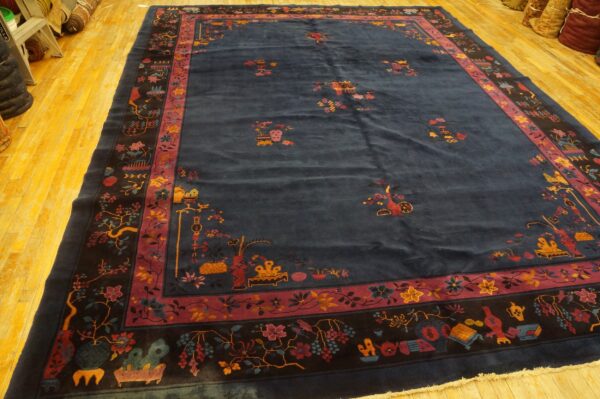 High-pile navy rug displaying detailed magenta and gold floral and object motifs on a bright wood floor.