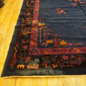 Navy blue rug with a detailed magenta and black floral border rests on shiny yellow wooden floors.