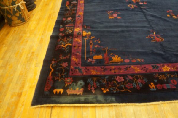 Navy blue rug with a detailed magenta and black floral border rests on shiny yellow wooden floors.