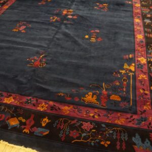 Dark blue high-pile rug featuring a scattered floral pattern and a multi-banded red and black border on wood floors.