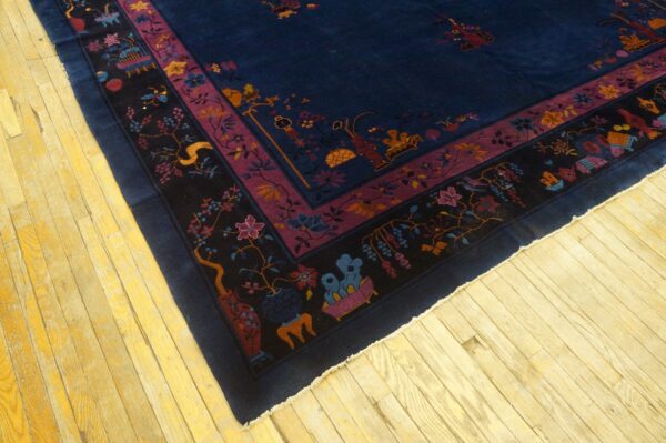 Corner view of a navy rug featuring purple, black, and multicolored borders on light wooden flooring.