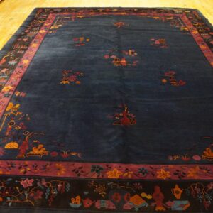 Deep indigo rug with scattered floral and vessel motifs, framed by intricate black and mauve borders.