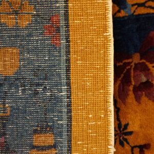 Contrasting textures of a rug: flat blue backing/border and high pile front in navy, gold, red, and purple.