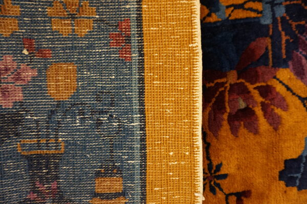 Contrasting textures of a rug: flat blue backing/border and high pile front in navy, gold, red, and purple.