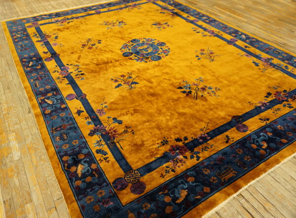 Vibrant gold high-pile rug featuring a complex blue border and colorful floral patterns on wood floors.