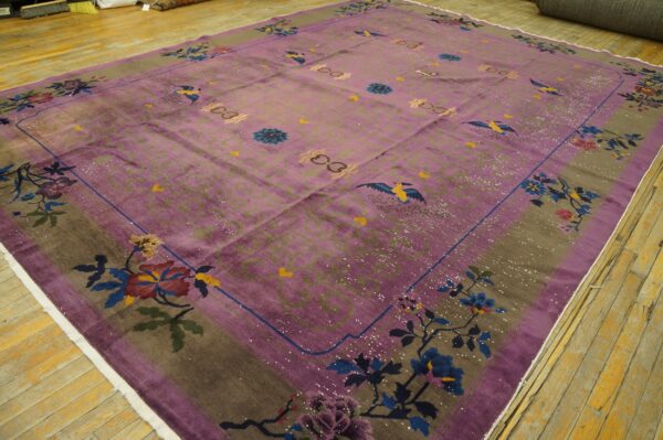 Mauve rug with colorful floral and bird patterns bordered by taupe, resting on distressed hardwood floors.