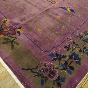 Detail of a purple and brown rug with floral and bird patterns on rustic yellow wooden flooring.