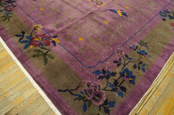 Detail of a purple and brown rug with floral and bird patterns on rustic yellow wooden flooring.