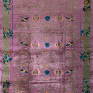 Shimmering magenta rug displaying scrolling green patterns and colorful floral and bird motifs on a green border.
