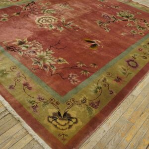 Low-pile dusty rose rug featuring sprawling botanical motifs and an olive border on light wood flooring.