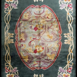 Teal rug with a large floral oval medallion and stylized multicolored vine borders.